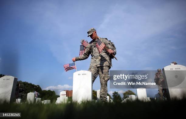 Members of the 3rd U.S. Infantry Regiment place American flags at the graves of U.S. Soldiers buried in Section 60 at Arlington National Cemetery in...