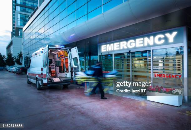 paramedics taking patient on stretcher from ambulance to hospital - ambulance stockfoto's en -beelden