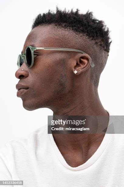 african-american man in white t-shirt wearing sunglasses against white background. - sunny side stock pictures, royalty-free photos & images