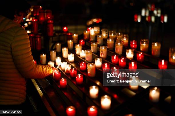 Worshipper lights a candle at the Basilica of Saint Therese of Lisieux on Christmas Day on December 25, 2022 in Lisieux, France. The Basilica of...