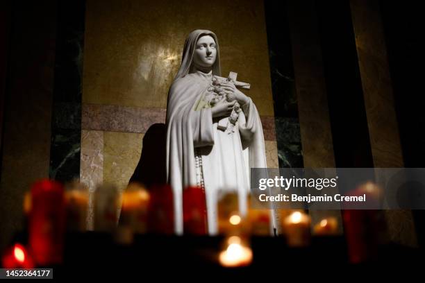 Candles lit by worshippers burn under a statue of Saint Therese at the Basilica of Saint Therese of Lisieux on Christmas Day on December 25, 2022 in...