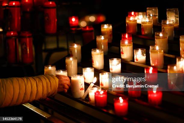 Worshipper lights a candle at the Basilica of Saint Therese of Lisieux on Christmas Day on December 25, 2022 in Lisieux, France. The Basilica of...