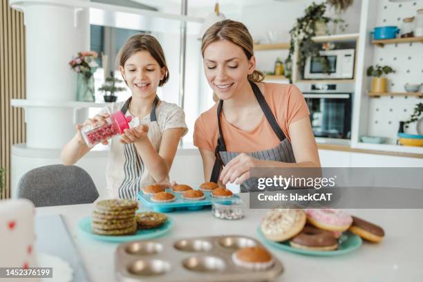 mother and daughter in the kitchen making sweets together - decorating a cake stock pictures, royalty-free photos & images