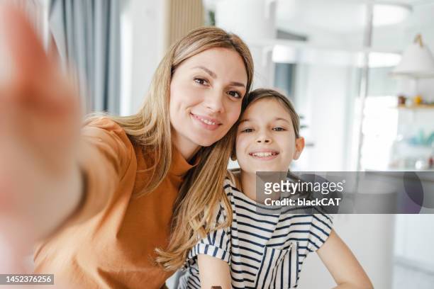 mother and daughter taking a selfie at home - mother daughter webcam stockfoto's en -beelden