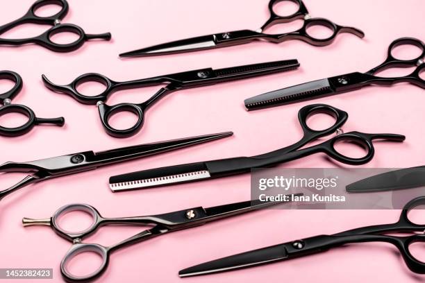 collection of different black hairdressing scissors on trendy pastel pink background. working tools for hairdressers. pattern. - forbici per parrucchieri foto e immagini stock
