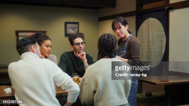 waitress taking orders from group of multi-ethnic tourist friends in japanese style pub izakaya - man party night bar posing stock pictures, royalty-free photos & images