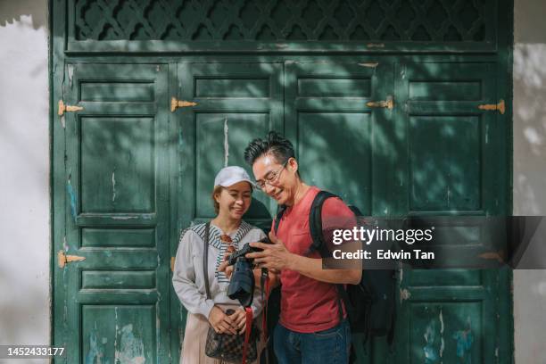 asian chinese couple tourist checking image captured with lcd screen of camera in front of islamic architecture building wooden door - asian photographer stock pictures, royalty-free photos & images