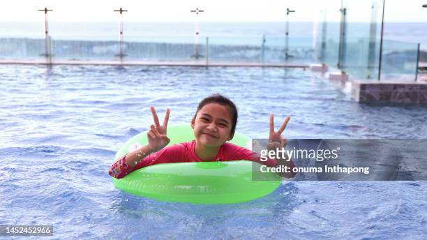 ein mädchen spielt mit aufblasbarem ring im schwimmbad, sommerferien - tube girl stock-fotos und bilder