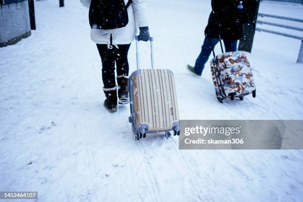 snow cover on the road and tourist lug the luggage walking on the road in  winter season at sapporo city hokkaido japan - snow festival stock-fotos und bilder