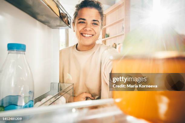 woman taking food from refrigerator. - nevera abierta fotografías e imágenes de stock