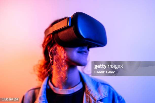 neon portrait of young woman wearing virtual reality headset - virtual reality headset stockfoto's en -beelden