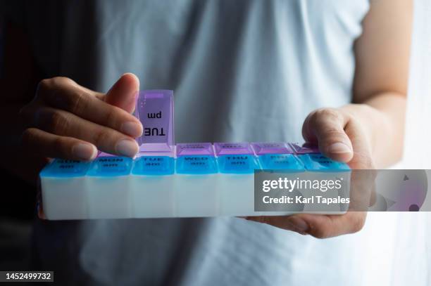 a southeast asian woman is holding a pill box - tablettenschachtel stock-fotos und bilder