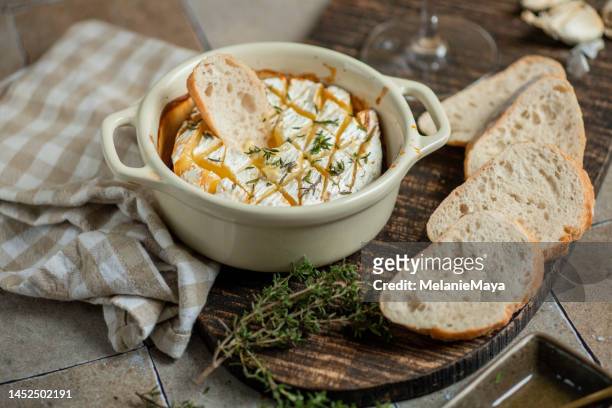 gebackener brie-käse mit thymiankräutern, honig und weißwein in rustikaler küche mit baguettebrot - brie stock-fotos und bilder