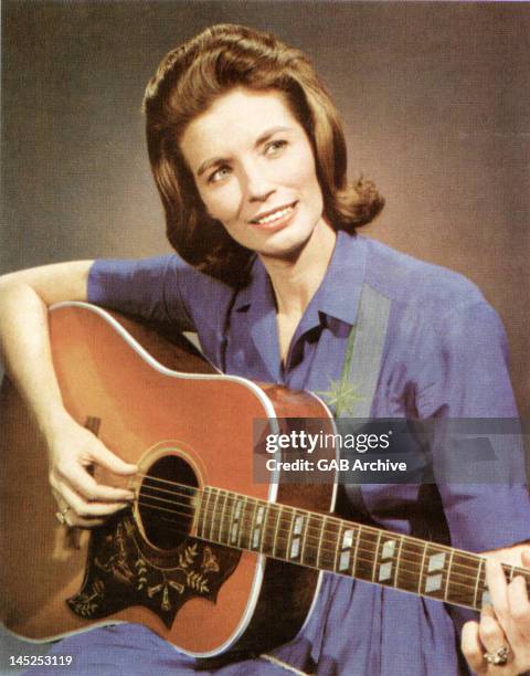 Photo of American singer and actress June Carter posed playing an acoustic guitar circa 1965.