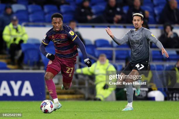 Ethan Laird of Queens Park Rangers runs with the ball as Callum Robinson of Cardiff City reacts during the Sky Bet Championship between Cardiff City...