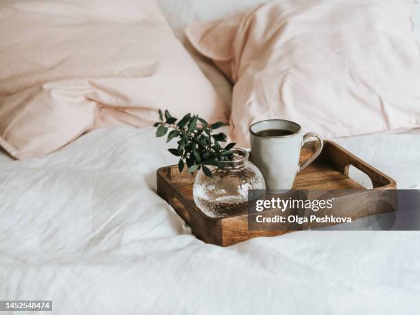 cup of coffee and glass vase with branch on wooden tray - breakfast in bed tray stock-fotos und bilder
