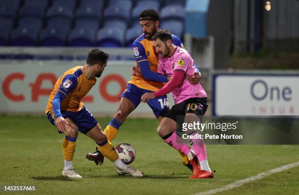 Danny Hylton of Northampton Town attempts to move with the ball past James Perch and Stephen McLaughlin of Mansfield Town during the Sky Bet League...