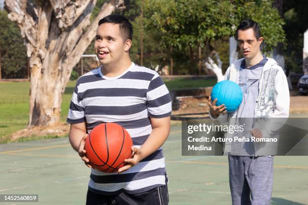 young man with down syndrome with a basketball ready to dunk - disability rights stock pictures, royalty-free photos & images