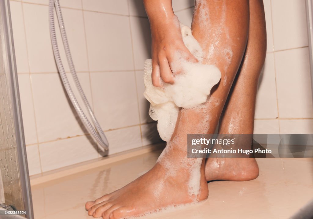 Woman washing her legs with gel in the shower