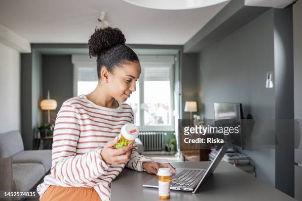 young woman searching online for more information about her medical condition - prescription stock pictures, royalty-free photos & images