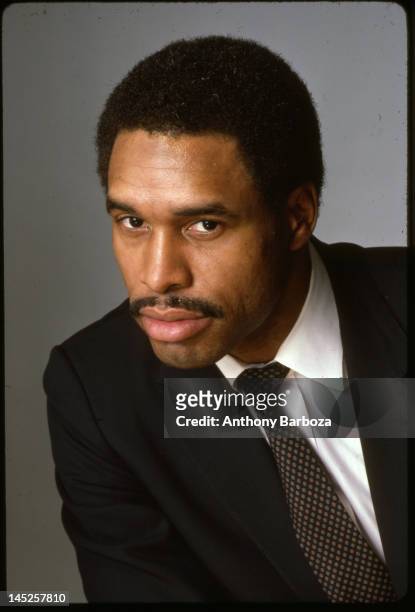 Portrait of American baseball player Dave Winfield, of the New York Yankees, dressed in a suit and tie as he poses against a gray background, 1980s.