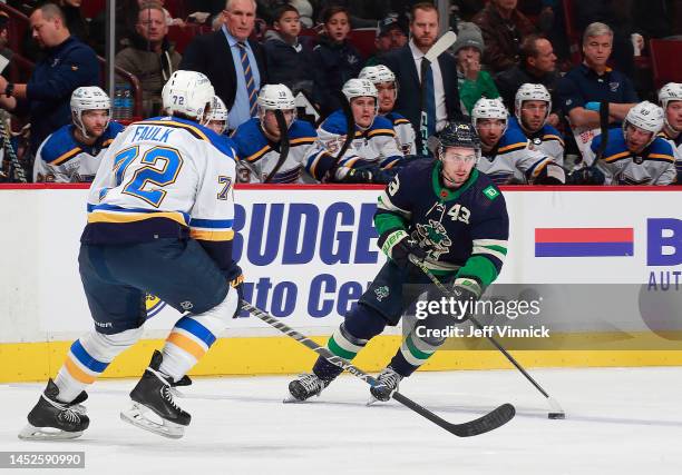 Justin Faulk of the St. Louis Blues looks on as Quinn Hughes of the Vancouver Canucks skates up ice with the puck during their NHL game at Rogers...