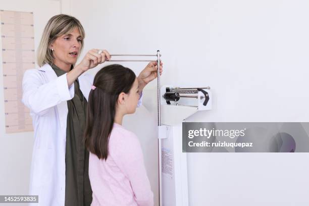 female nutritionist doctor measuring the height and weight of a little boy in her medical office - measure length stock pictures, royalty-free photos & images