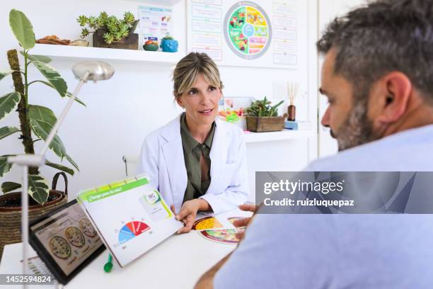 female nutricionist doctor in her office in a medical consultation with overweight male patient - nutritionist stockfoto's en -beelden
