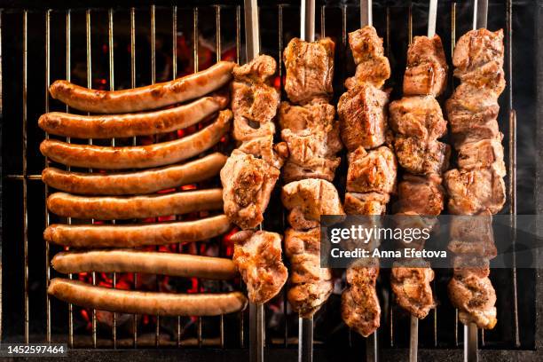 meat on skewers and sausages are cooking on the grill. concept of country picnic. photography from above - metal grate stock pictures, royalty-free photos & images