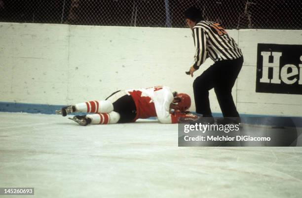 Paul Henderson of Canada lays on the ground after crashing into the boards as the referee checks him out during Game 5 of the 1972 Summit Series on...