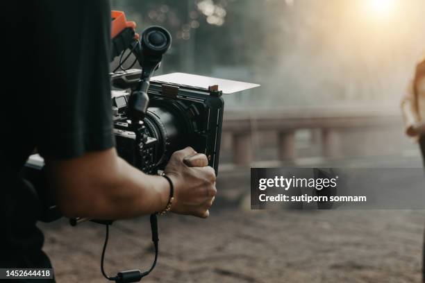 close up hands holding cinema camera shooting - film stock-fotos und bilder