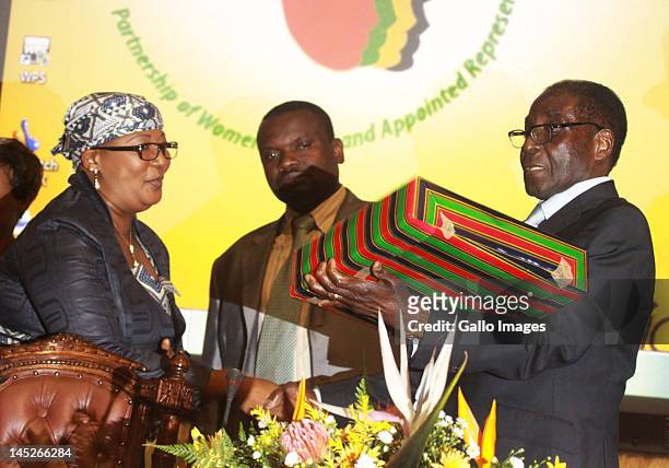 Zimbabwean President Robert Mugabe receives a token of appreciation from Thokozani Khupe, President of Global Power Women Network and deputy Prime...
