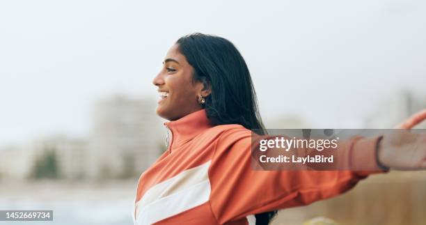 happy indian woman, outdoor freedom and arms out, ocean wind and breathe fresh air with purpose or happiness, motivation and wellness, peace and hope. smile, optimism and dream, success in nature - souls of my young sisters press reception stockfoto's en -beelden