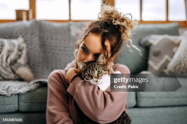 jeune femme se lie avec son chat dans un appartement - domestic animals photos et images de collection