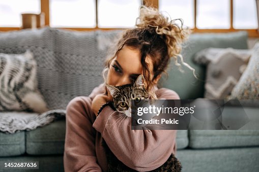 Young woman bonding with her cat in apartment Young woman bonding with her cat in apartment