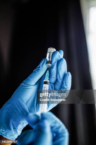使い捨て手袋を着用し、ワクチンまたは注射が入った注射器を持つ看護師 - injecting ストックフォトと画像
