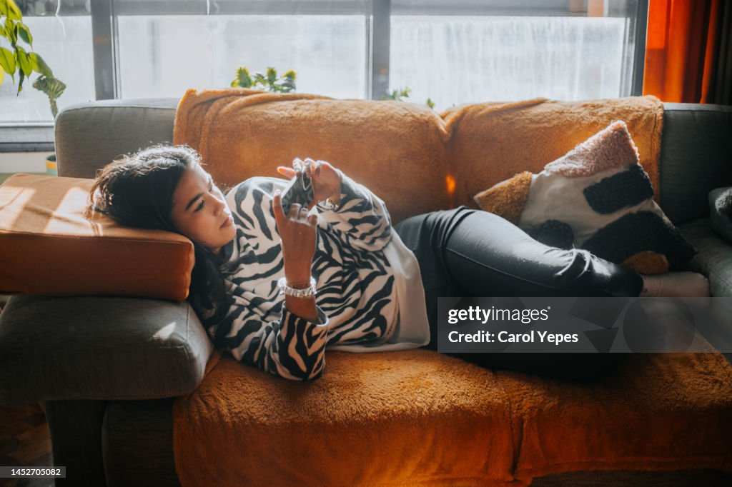 Young female teenager using cell phone at home.