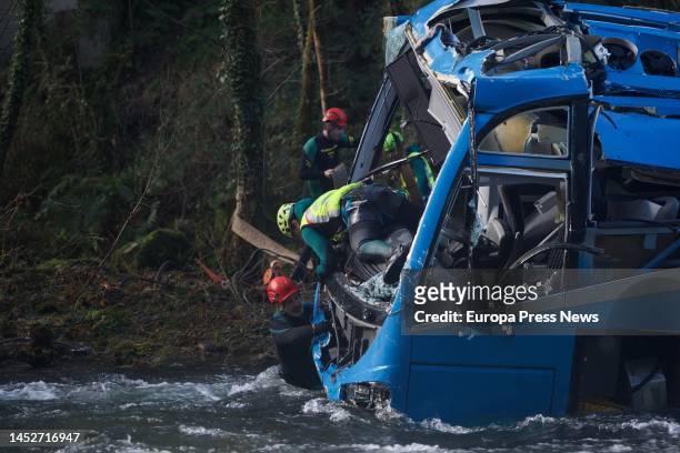 Several members of the Special Group of Underwater Activities of the Civil Guard participate in the work of lifting the bus accident to remove it...