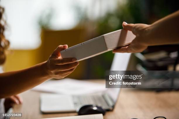 mujer sentada en su escritorio en la oficina y recibiendo un paquete de un repartidor - business person handing over a letter fotografías e imágenes de stock