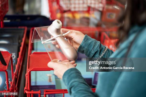 woman observes a sex toy in a store to pleasure herself, satisfaction choice, satisfayer object - feet sucking stock pictures, royalty-free photos & images