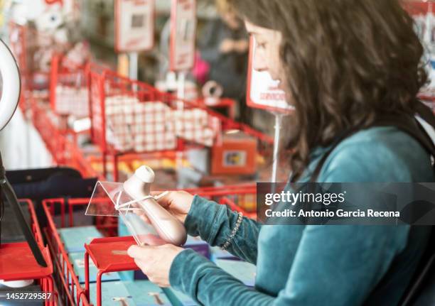 woman observes a sex toy in a store to pleasure herself, satisfaction choice, satisfayer object - vibrator stock-fotos und bilder