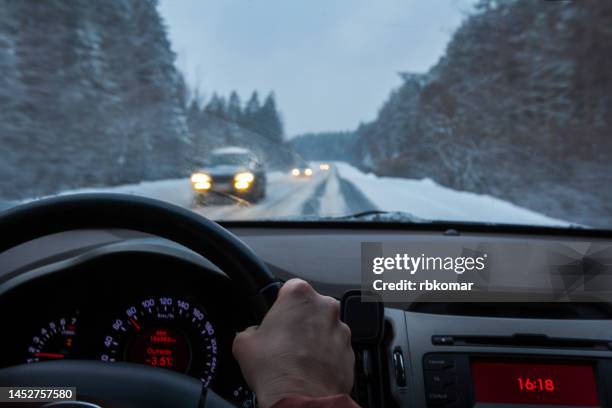 winter driving - view through the windshield on a snowy road at dusk - punto di vista del guidatore foto e immagini stock