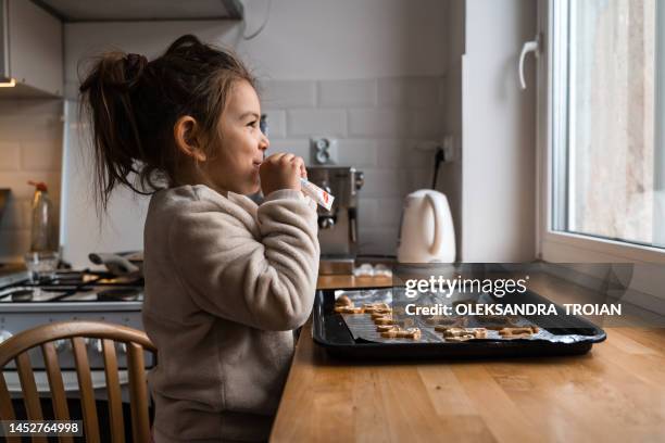 child girl cooking gingerbread cookies and drawing with icing at home. christmas tradition - jahreszeit stock-fotos und bilder