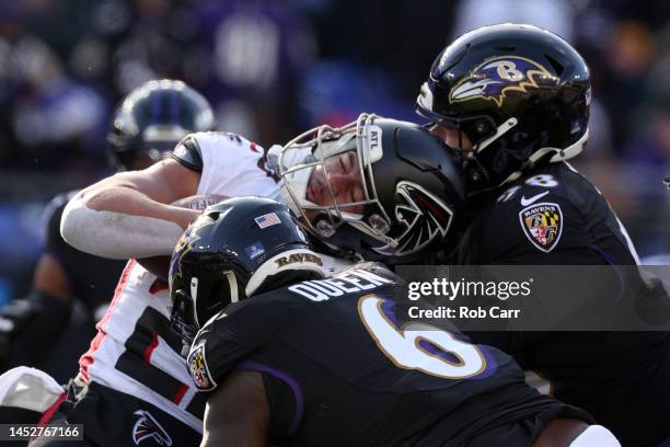 Running back Tyler Allgeier of the Atlanta Falcons is tackled by defensive tackle Travis Jones and linebacker Patrick Queen of the Baltimore Ravensat...