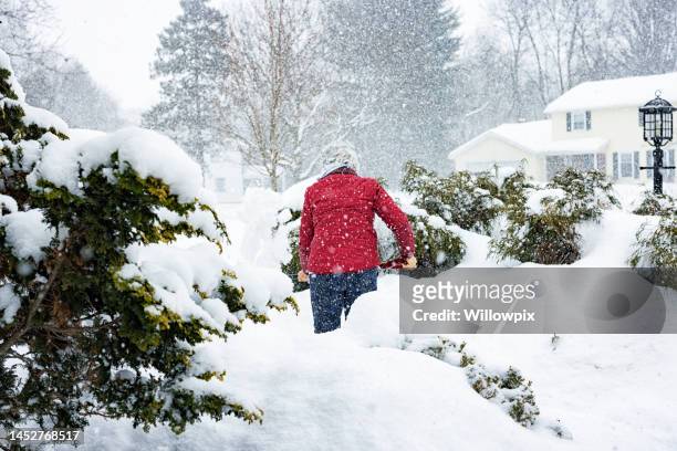 starke aktive rote jacke senior frau schaufeln winter schneesturm schnee - snow shovel stock-fotos und bilder