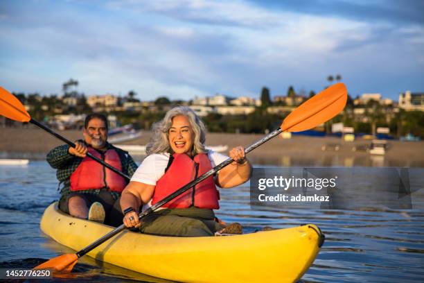 senior hispanic couple kayaking - older person kayaking stock pictures, royalty-free photos & images