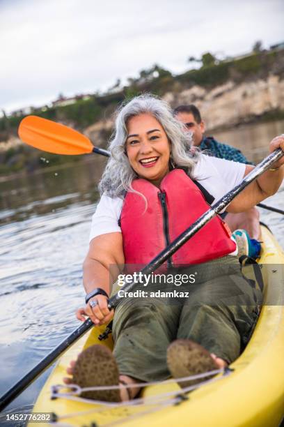 senior hispanic couple kayaking - older person kayaking stock pictures, royalty-free photos & images