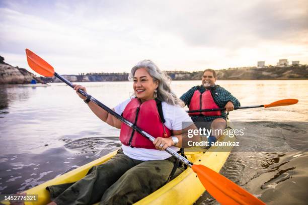 senior hispanic couple kayaking - older person kayaking stock pictures, royalty-free photos & images