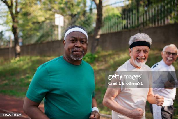 fitte aktive senioren beim morgendlichen lauf auf dem outdoor-trainingsplatz - 3 old men jogging stock-fotos und bilder