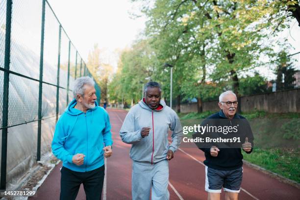 diverse active seniors doing jogging workout on outdoor sports court - 3 old men jogging stock pictures, royalty-free photos & images